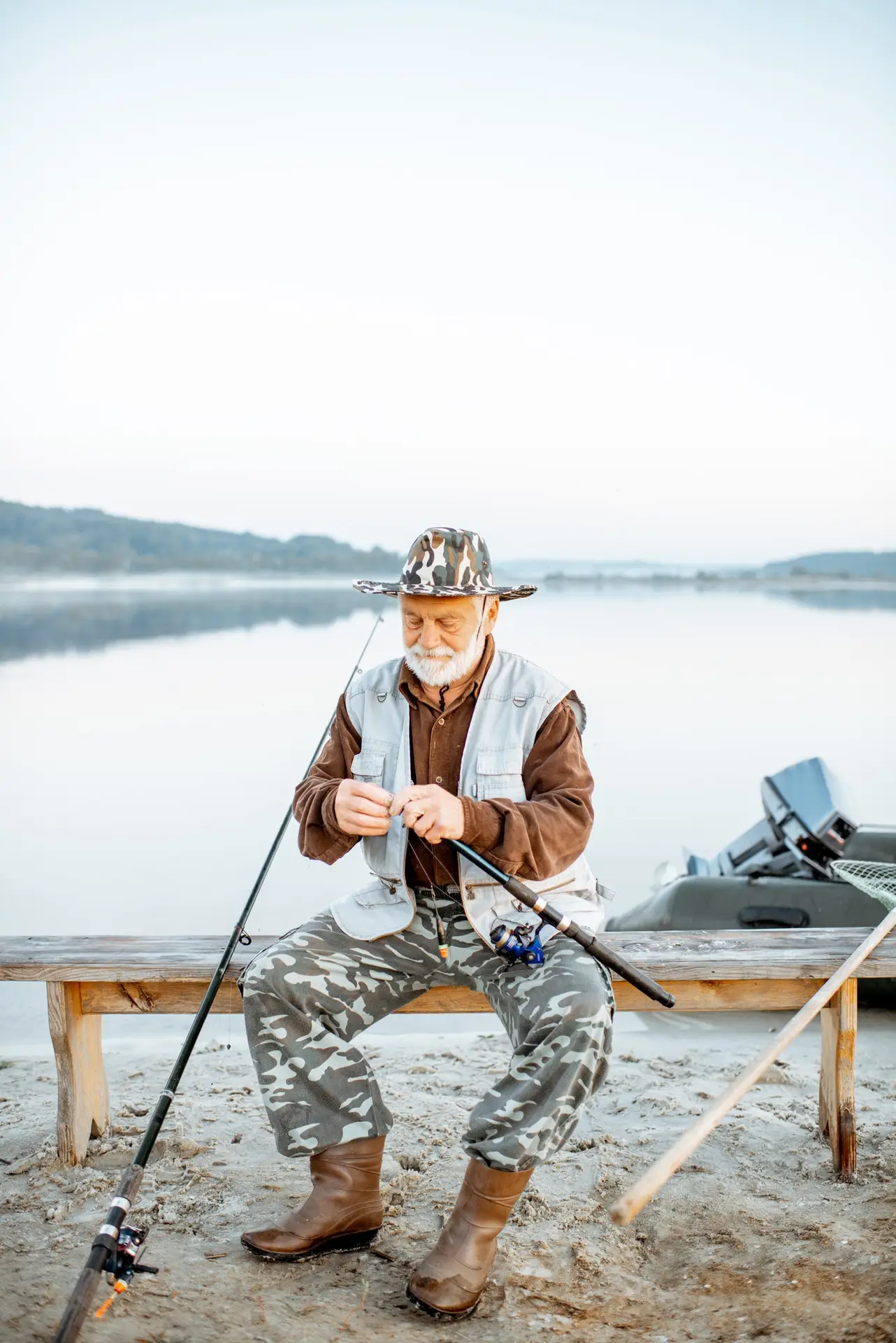 Pescador preparando su equipo junto a un lago en calma antes de una jornada de pesca